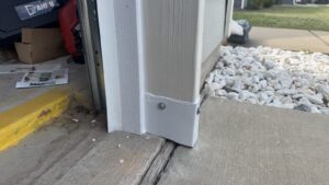 A formed sheet metal guard fixed over the bottom garage door corner, closing the triangular gap rats were using.